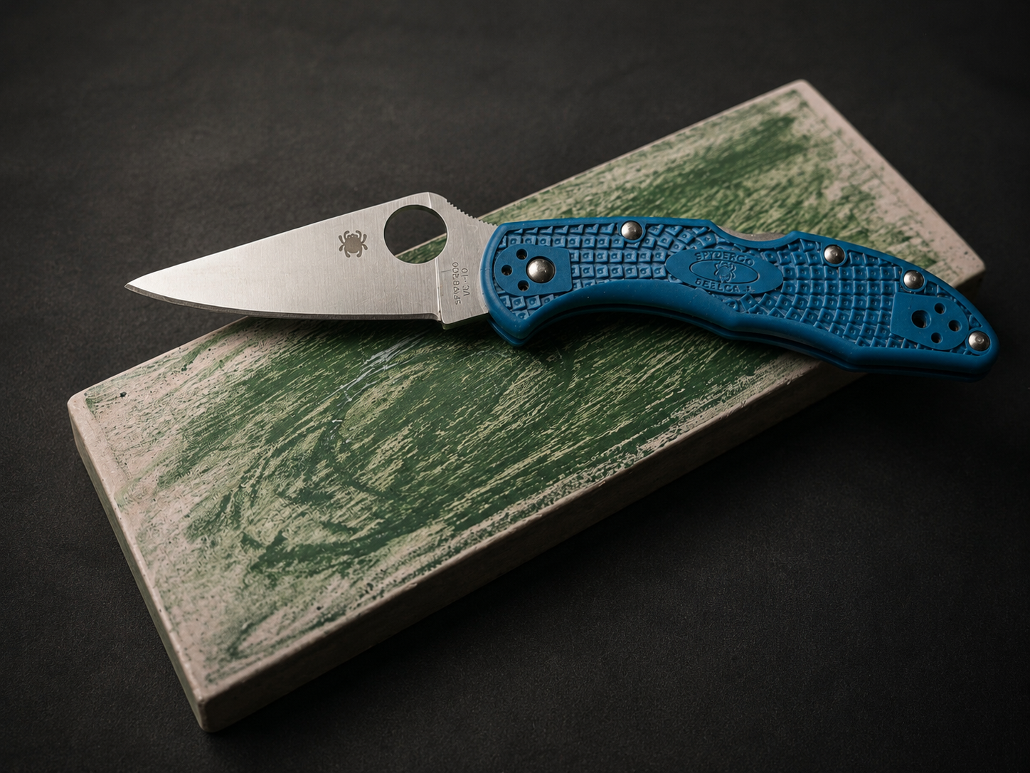 Blue handled folding knife resting on sharpening block